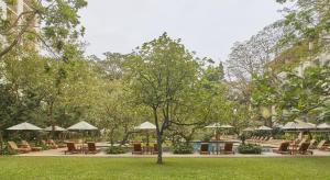 a park with chairs and tables and umbrellas at The Dharmawangsa Jakarta in Jakarta