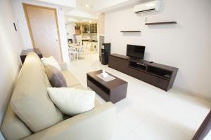 a living room with a couch and a television at Apatel The Mansion Jasmine Tower Aurora J31J in Jakarta