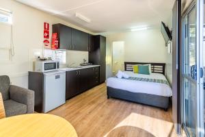 a bedroom with a bed and a kitchen with a microwave at Ingenia Holidays South West Rocks in South West Rocks
