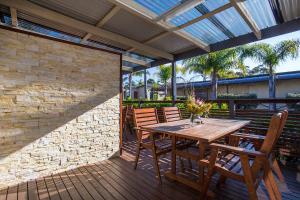 a wooden table and chairs on a wooden deck at The Mook Mollymook in Mollymook