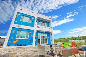a blue and white building with chairs in front of it at Penghu Color FIsh Homestay in Huxi