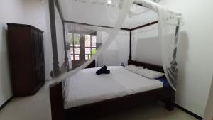 ein Schlafzimmer mit einem Himmelbett mit einer Katze drauf in der Unterkunft Bandulas Beach House in Hikkaduwa