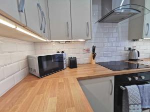 a kitchen with a microwave on a wooden counter top at Spacious 4BR Home with Garden, Swansea in Swansea