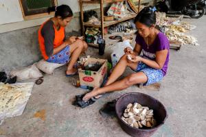 zwei Frauen sitzen auf dem Boden mit einem Korb Essen in der Unterkunft Griya Erlangga Homestay in Yogyakarta