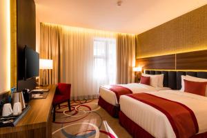 a hotel room with two beds and a television at Ramada Hotel & Suites by Wyndham Yerevan in Yerevan