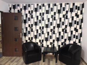 two black chairs next to a wall with a checkerboard pattern at Apartament Untold in Turda