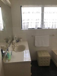 a white bathroom with a sink and a mirror at The Gardens' Treasure in Auckland