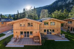 a large wooden house with a deck with chairs at Zugspitz Lodge in Ehrwald