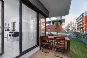 patio z krzesłami, stołem i szklanymi drzwiami w obiekcie Apartments Cracow Rakowicka by Renters w Krakowie