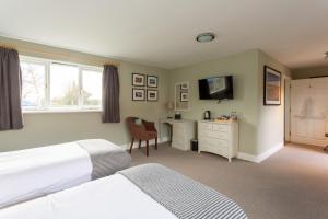 a bedroom with two beds and a desk and a tv at The Plough in Wangford