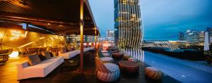 a rooftop bar with couches and tables and a city skyline at Naumi Hotel in Singapore