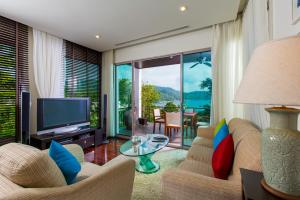 - un salon avec une télévision, un canapé et une table dans l'établissement Kata gardens penthouse seaview with rooftop pool 8C, à Kata Beach