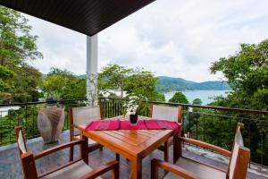 a wooden table and chairs on a balcony with a view at Kata gardens penthouse seaview with rooftop pool 8C in Kata Beach