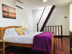 a bedroom with a bed with a purple blanket on it at Casa do Lugar da Ribeira in Ribeira Brava