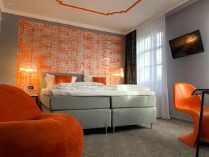 ein Schlafzimmer mit einem Bett und einer orangefarbenen Wand in der Unterkunft Hotel Maxplatz in Hof