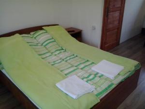 a green bed with two towels on top of it at Katica Vendégház in Békéscsaba