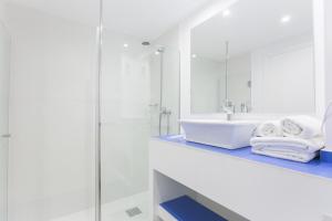 a white bathroom with a sink and a mirror at Guya Wave Hotel in Cala Ratjada