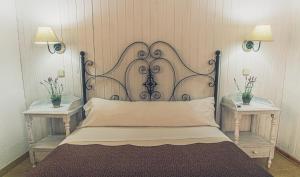 a bed with a metal headboard in a room with two tables at Hotel la Muñequilla in Miraflores de la Sierra