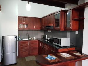 ワッタラにあるEldorado Apartments 3BR Apart F2P3のキッチン(木製キャビネット、電子レンジ、冷蔵庫付)
