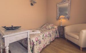 
a room with a bed, chair, lamp and a mirror at Hotel la Muñequilla in Miraflores de la Sierra
