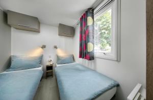 two beds in a room with a window at KNAUS Campingpark Bad Dürkheim in Bad Dürkheim