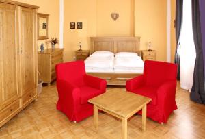 a bedroom with two red chairs and a bed at Zámek Libouň in Louňovice pod Blaníkem