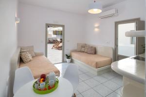 a white living room with a bed and a table at Olive Tree Suites in Fira