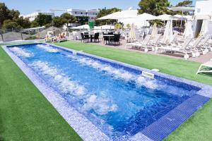 een zwembad met witte stoelen en een tafel en stoelen bij Hotel Club Es Talaial in Cala d´Or