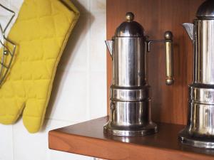 2 pitchers en métal sur une étagère avec un oreiller jaune dans l'établissement Casa con vista Forte - tra lago e monti, à Rivoli Veronese