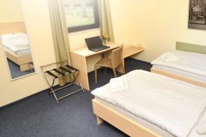 a room with two beds and a desk with a laptop at Best Deal Airporthotel Weeze in Weeze