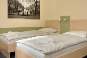 two beds with white sheets and towels on them at Best Deal Airporthotel Weeze in Weeze