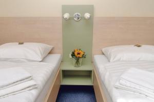 two beds in a room with a vase of flowers on a table at Best Deal Airporthotel Weeze in Weeze