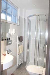 ein Bad mit einer Dusche, einem Waschbecken und einem WC in der Unterkunft Der Sailer Hotel & Restaurant in Obertauern