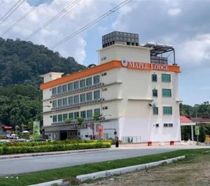 a white building with a sign on the side of it at Maple Lodge in Batu Pahat