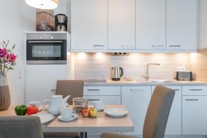 a kitchen with white cabinets and a table with fruit on it at Haus Dünenrose in Börgerende-Rethwisch