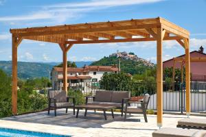 a wooden pergola with chairs and a pool at Motovun Villas in Motovun