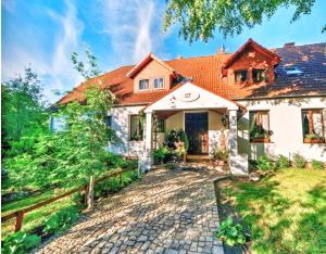 a house with a cobblestone driveway in front of it at Dworek Tradycja in Łobez