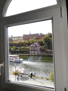 une fenêtre avec vue sur la rivière et un bâtiment dans l'établissement Le Cerf Vert, à Dinant