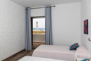 a bedroom with two beds and a window with a lighthouse at The Real Casa Atlantica Morro Jable By PVL in Morro del Jable