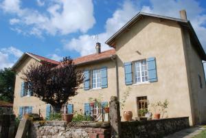 a house with blue windows and a stone wall at Chambres d'Hôtes Larrey in Audignon