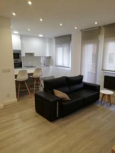 a living room with a black couch and a kitchen at Apartamento Ángela in Gijón