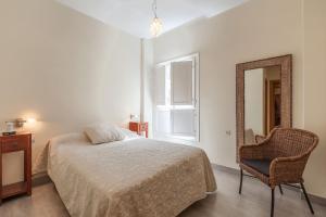 sypialnia z łóżkiem, lustrem i krzesłem w obiekcie Apartamento con encanto en el Barrio de Santa Cruz w Sewilli