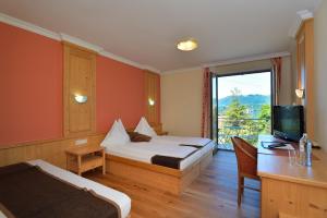 a hotel room with a bed and a desk and a television at Hotel Magerl in Gmunden