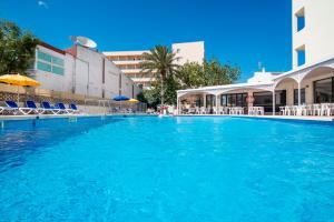 ein großer Pool mit Stühlen und ein Gebäude in der Unterkunft Hotel Santa Maria Playa in Cala Millor