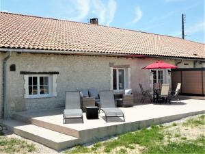 un patio con sillas y una sombrilla roja en Le Gite Sereine, en Berneuil