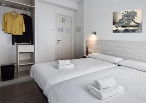 a white bedroom with two beds with towels on them at Hostal Lar in Burgos