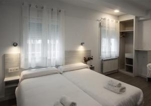 1 dormitorio con 1 cama blanca grande y toallas. en Hostal Lar, en Burgos