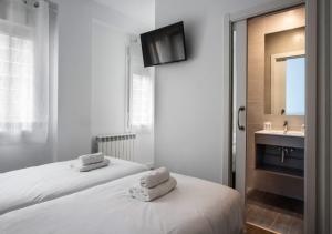 two beds in a room with a sink and a mirror at Hostal Lar in Burgos
