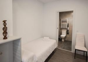 a white bedroom with a bed and a toilet at Hostal Lar in Burgos