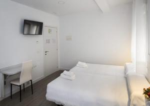 a room with two beds and a desk and a television at Hostal Lar in Burgos